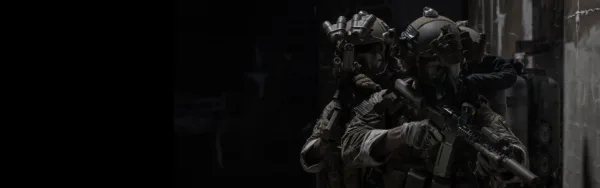 Soldiers in multicam uniforms with night vision and suppressed rifles clearing a dark room