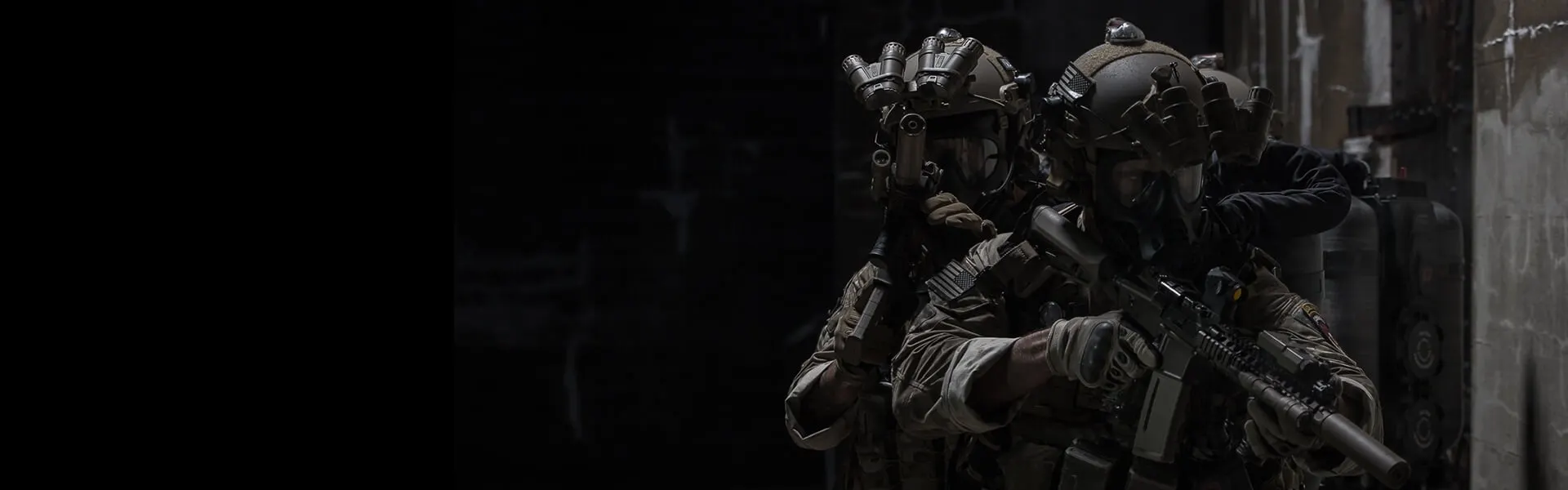 Soldiers in multicam uniforms with night vision and suppressed rifles clearing a dark room